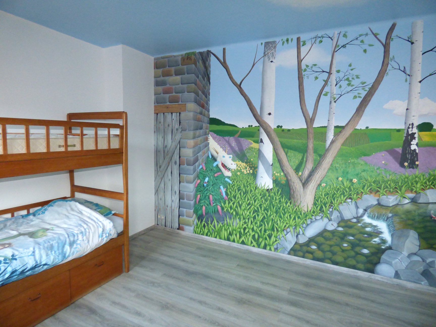 Peinture murale d'une chambre d'enfant: Trompe l'oeil réaliste d'une campagne avec un dragon sympathique